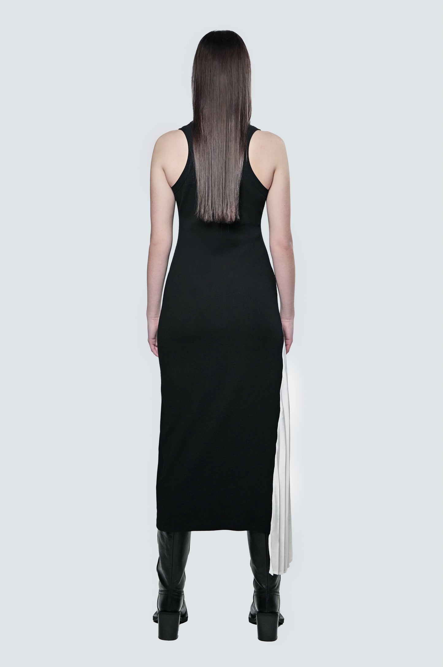 Back view of a black ribbed maxi dress with a fitted silhouette and contrast pleated panel.