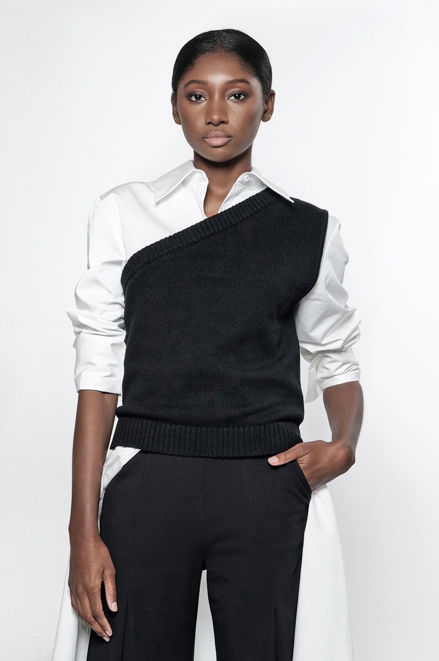 A model wearing a one shoulder asymmetric knit vest in black