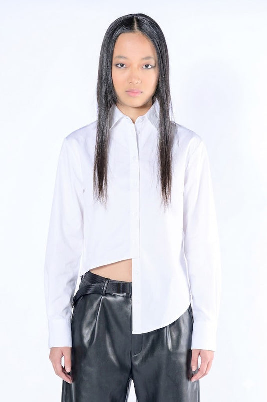 Model wearing white asymmetric button down shirt with leather pants against a white background.