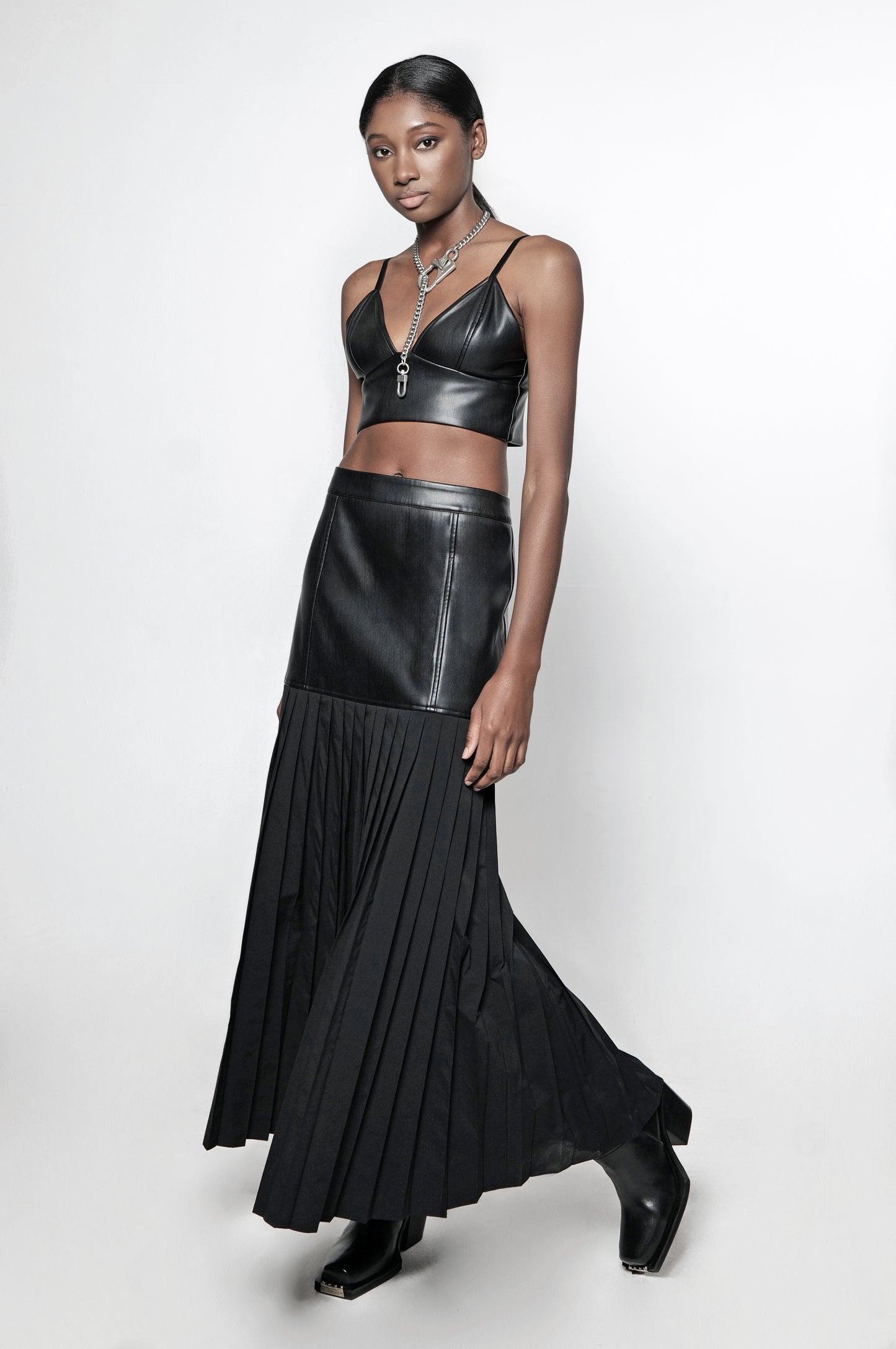 Model wearing black leather bralette and leather pleated maxi skirt