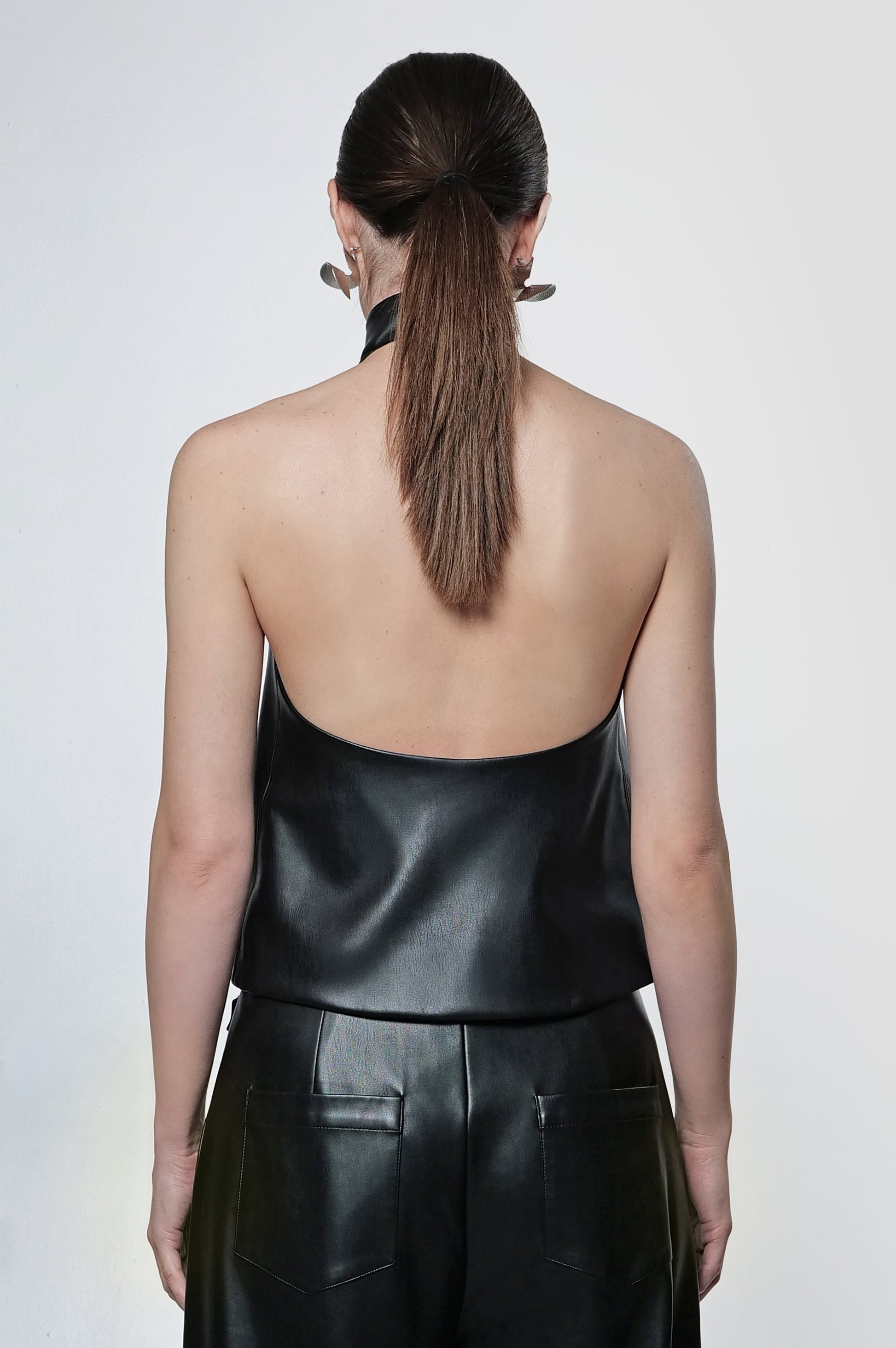 Model wearing black leather halter top with view of the back