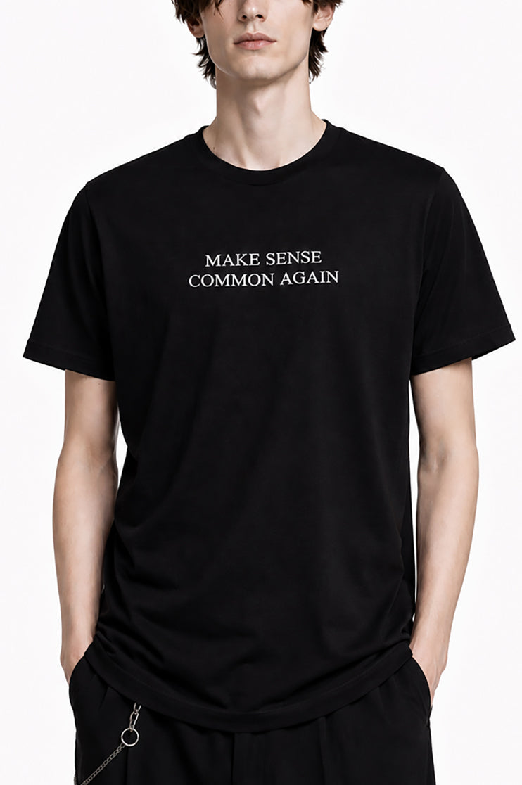 A man wearing a black t-shirt that says "Make Sense Common Again" against a white background