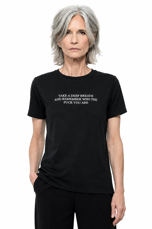 Woman wearing a black t-shirt that says "take a deep breath and remember who the fuck you are"