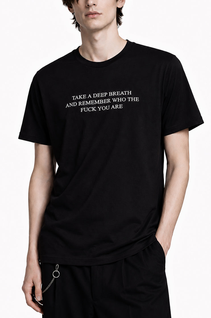 Man wearing a black t-shirt that says "take a deep breath and remember who the fuck you are"
