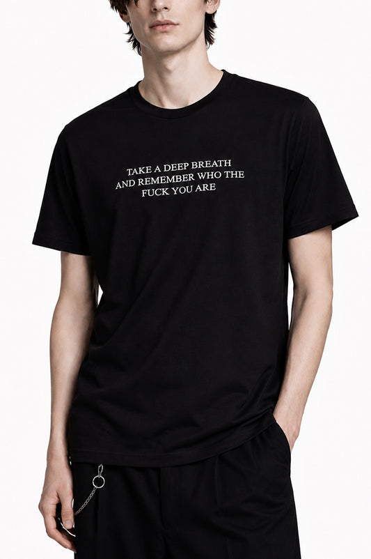 Man wearing a black t-shirt that says "take a deep breath and remember who the fuck you are"