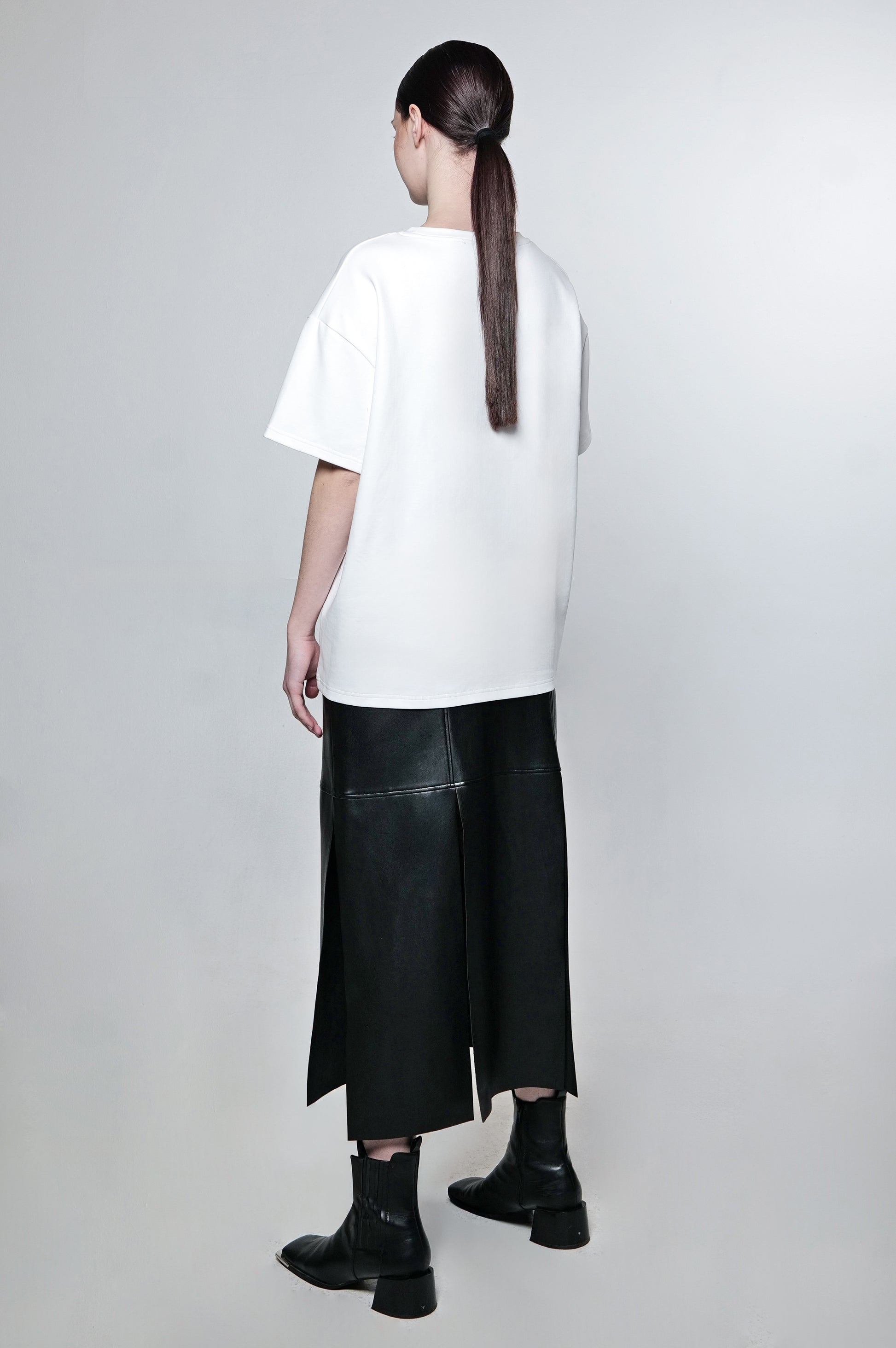 Back view of white oversized t-shirt and black leather skirt.